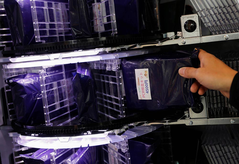 شخص من طاقم العيادة يُعيد تعبئة آلة البيع بُعدد الكشف | عبر رويترز